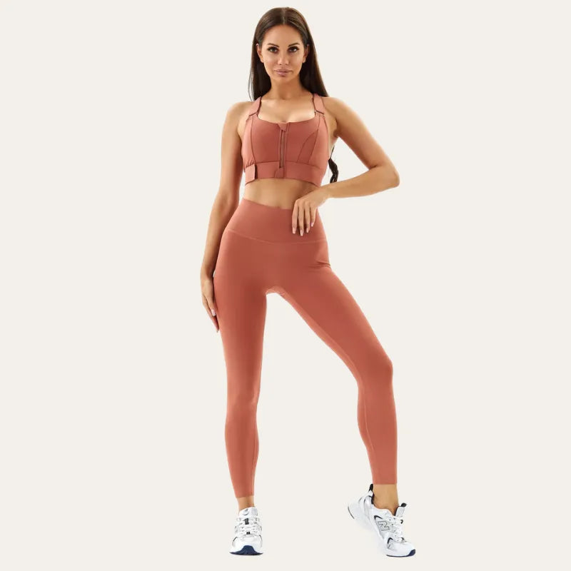 Modelo a usar o soutien desportivo Alba terracota com leggings a condizer e ténis brancos, com a mão na cintura