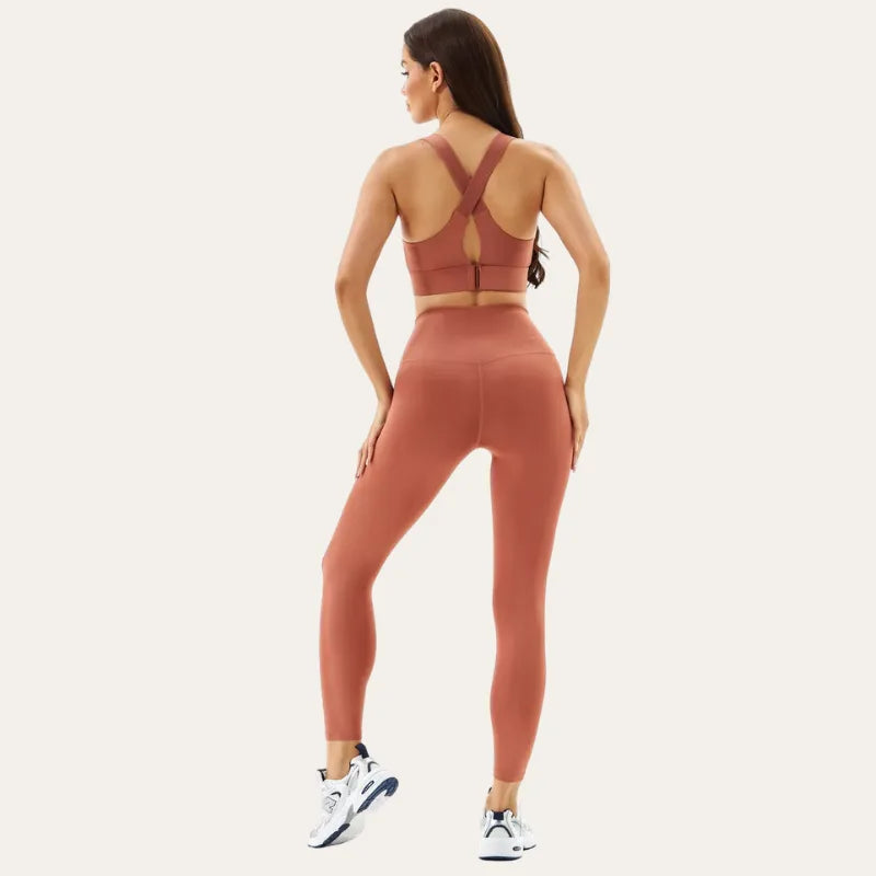 Mulher de costas a usar o soutien desportivo Alba terracota com leggings, a mostrar as alças cruzadas