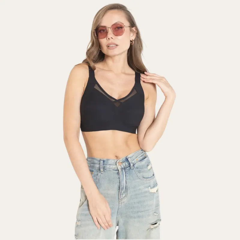 Mulher de óculos usando o Soutien Sávia preto, com recorte em tela no centro do decote e jeans