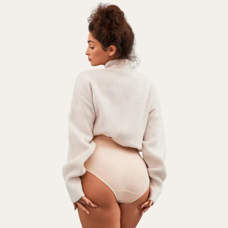 Vista traseira da modelo vestindo cuecas Pure bege de cintura subida com camisola oversized creme
