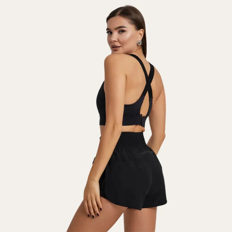 Mulher de costas, a olhar por cima do ombro, a usar o soutien desportivo Alba preto com calções